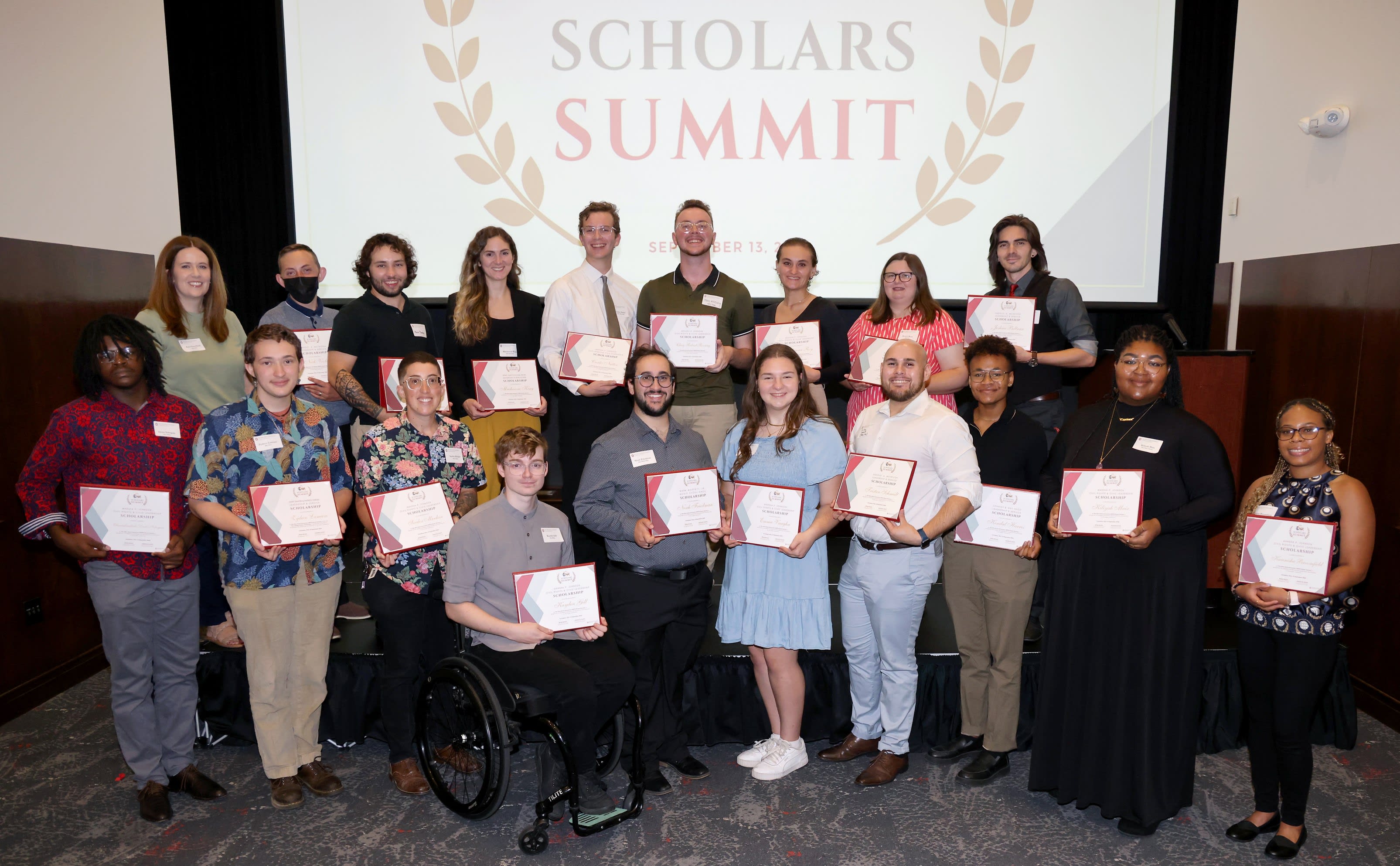 Group of 2024 Scarlet and Gay scholarship recipients standing inside holding their awards
