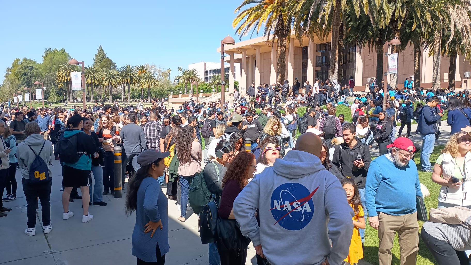 Crowd of people viewing a solar eclipse on the lawn of the University Library