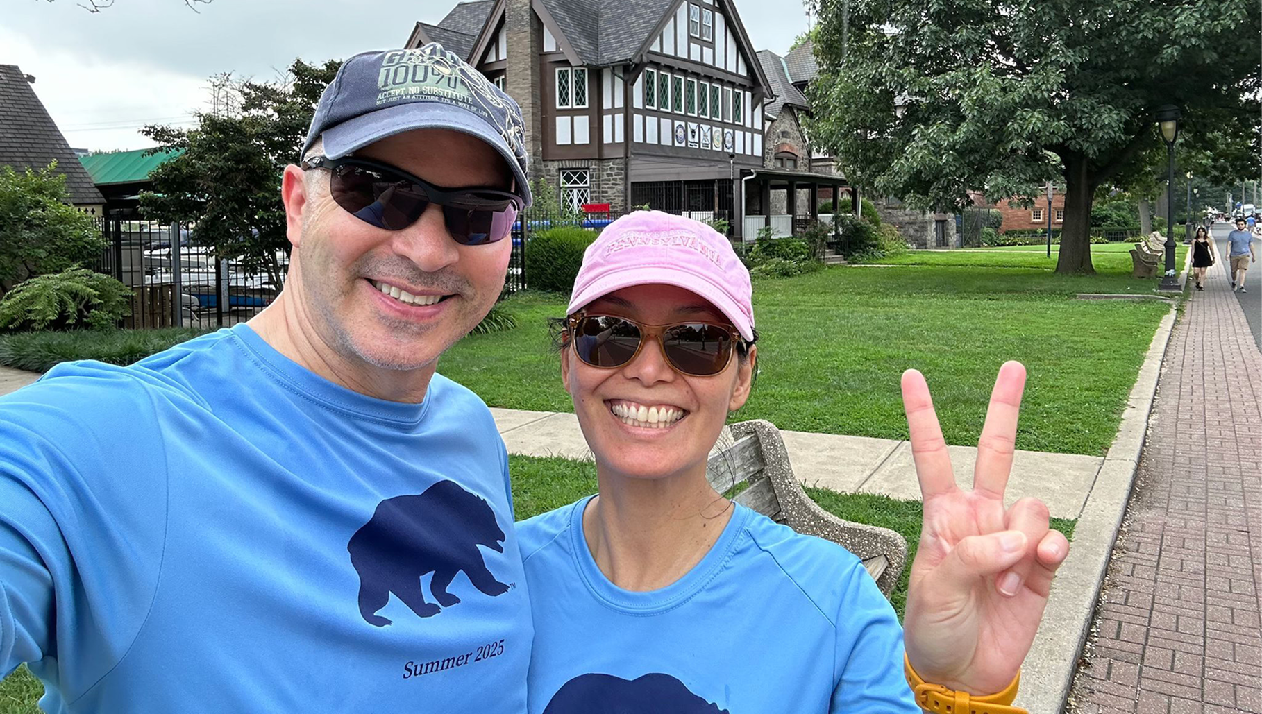 A man and woman in matching blue shirts smile at the camera