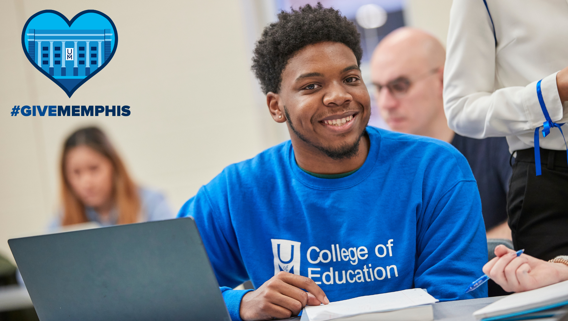 student smiling in class with the hashtag give memphis logo in the corner