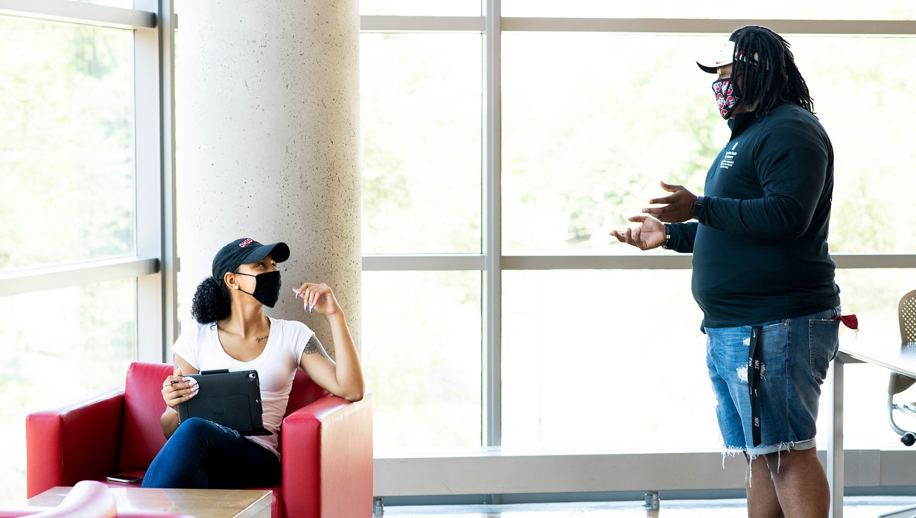 Two students wearing masks chatting while studying