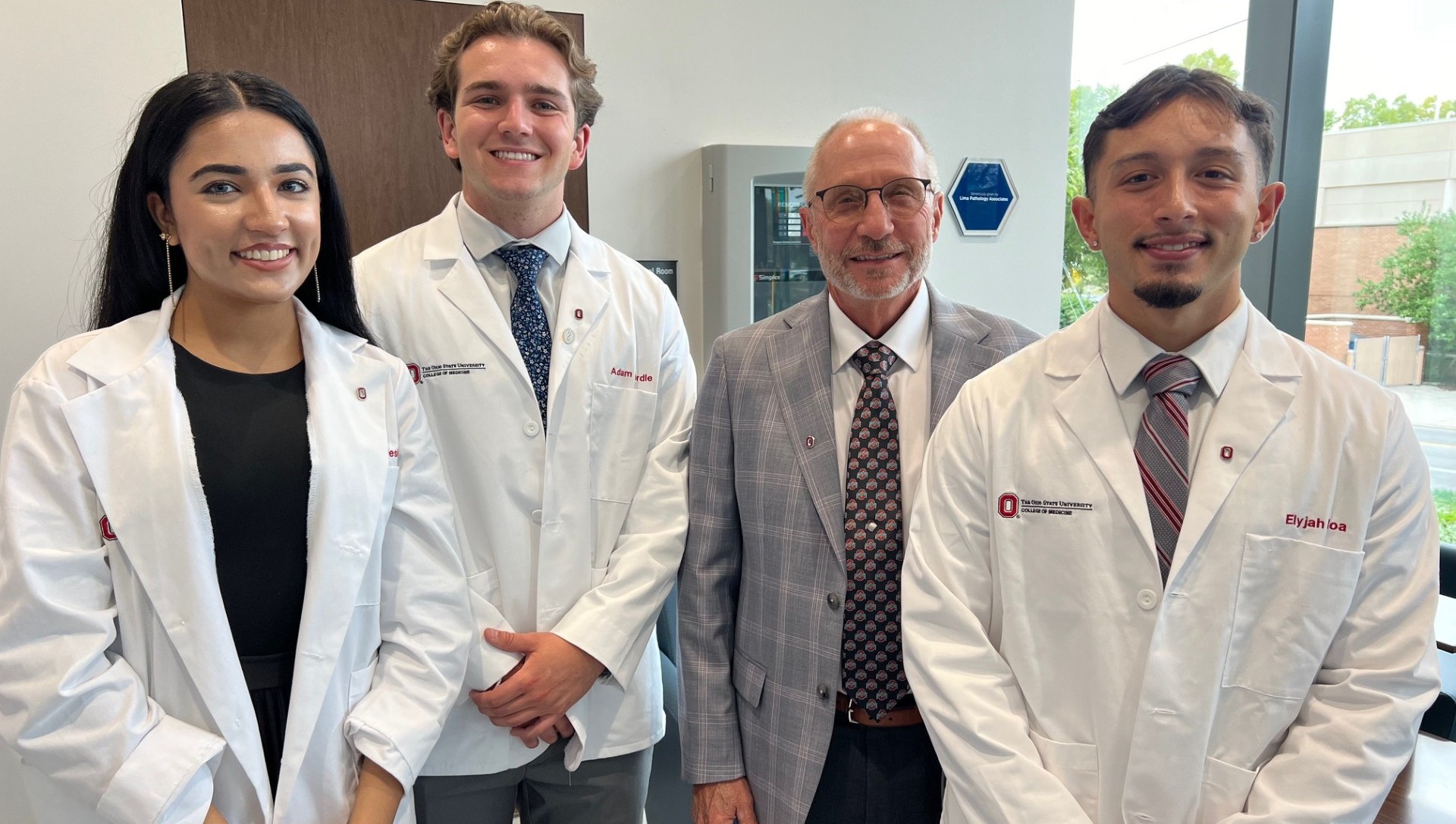 Three doctoral students standing with professor