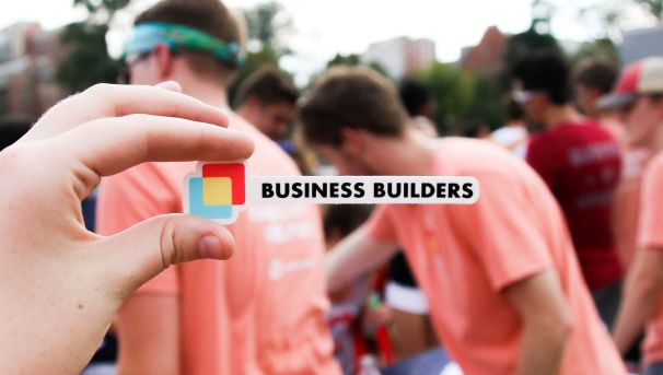 Business Builder's logo sticker, held against a background of volunteers