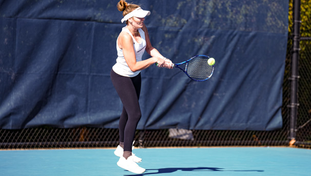 Monmouth Women's Tennis Student-Athlete making a backhand shot.