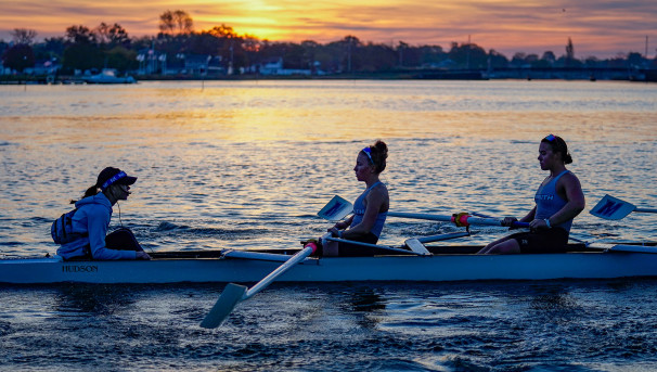 Monmouth Rowing student-athletes carrying an eight-person boat into the water for competition.