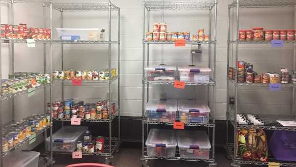 Grey, metal shelves in a food pantry, lined with various cans and goods for students