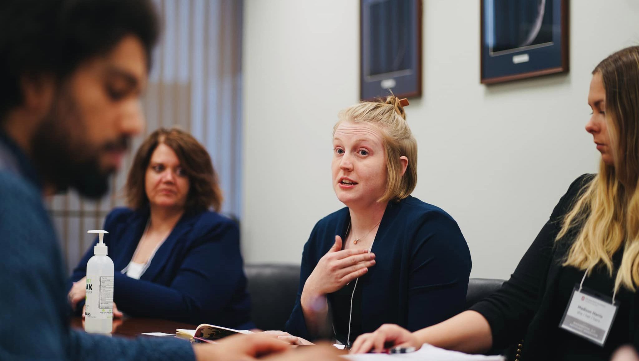 Group of four individuals sitting at a table discussing important topics