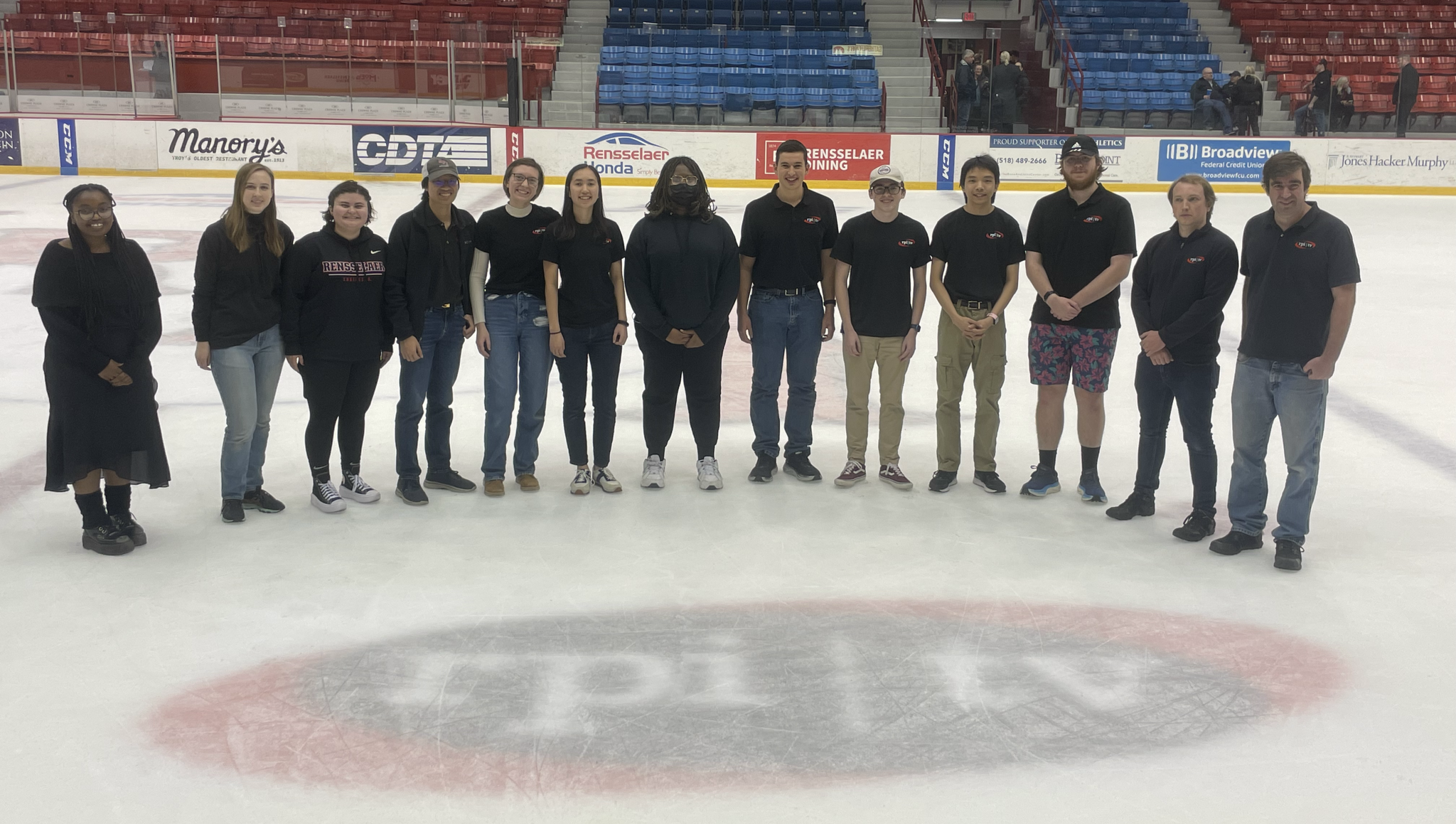 Members of RPI TV standing on the ice at Houston Field House by the RPI TV emblem in the ice.