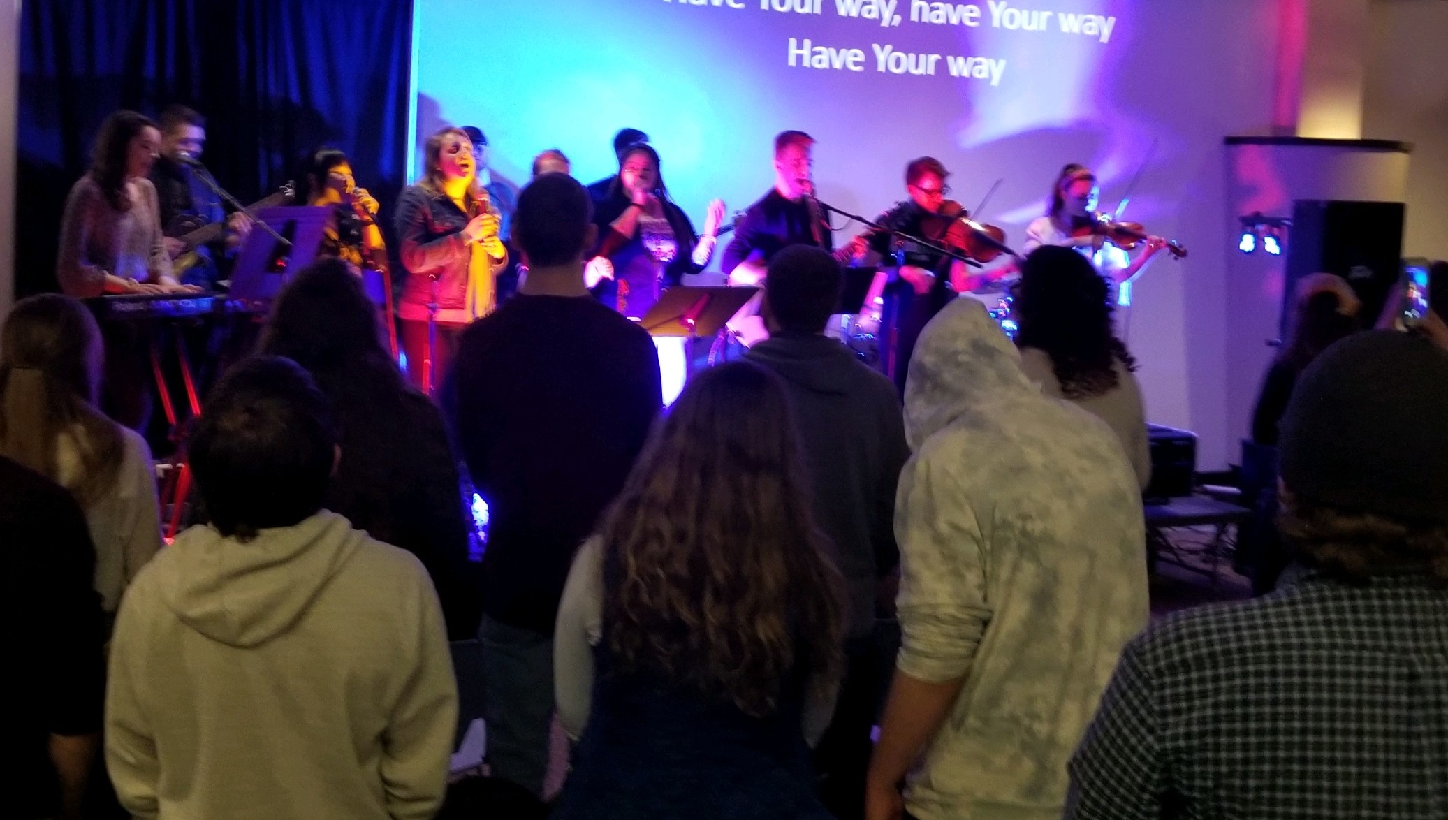 Students singing or playing various instruments on a stage