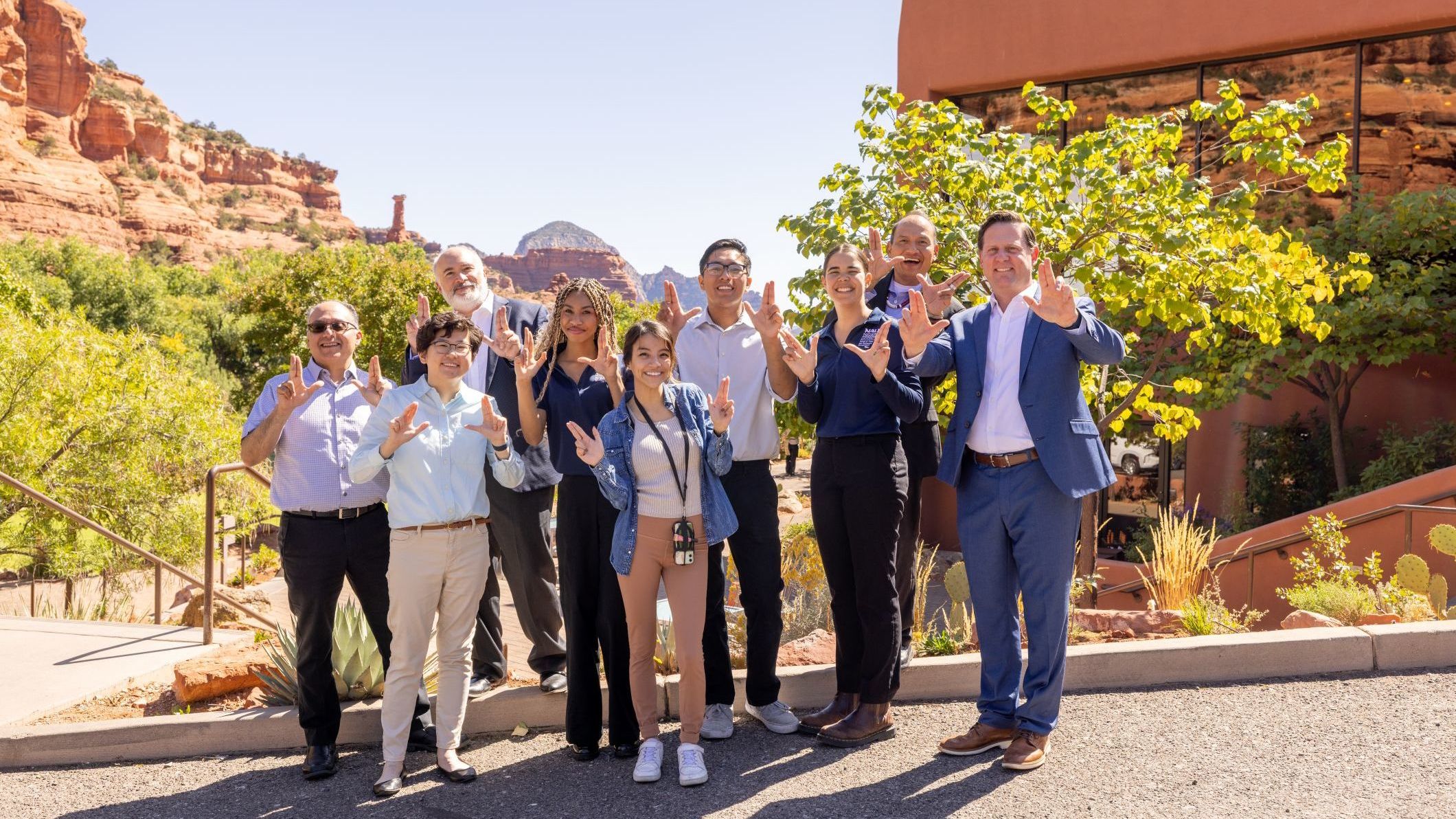 A group of HRM students and faculty holding up the LJ hand signs at Enchantment.