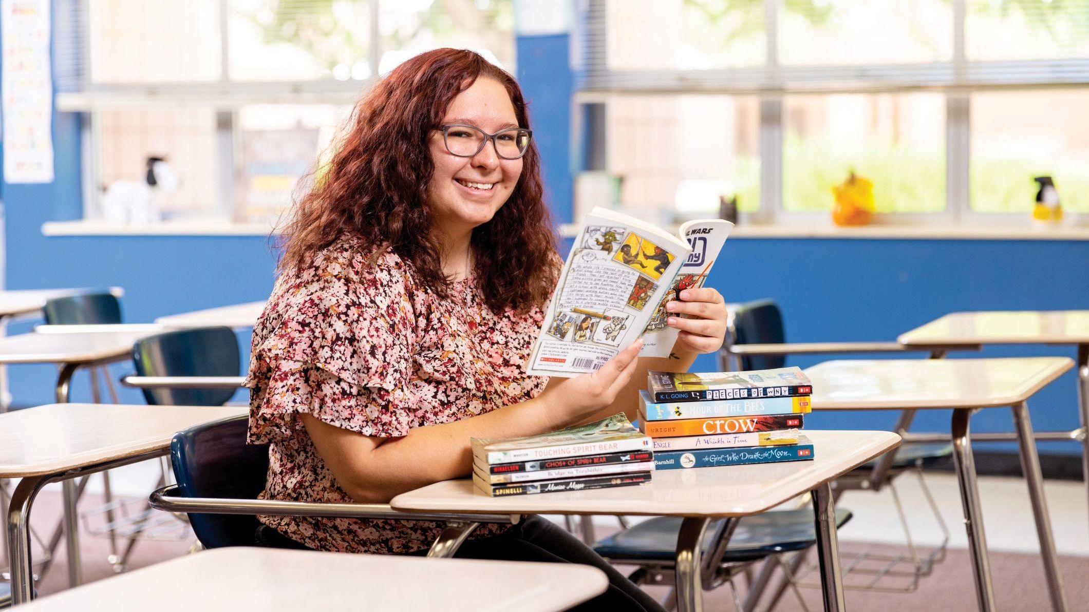 An NAU student smiling while reading books