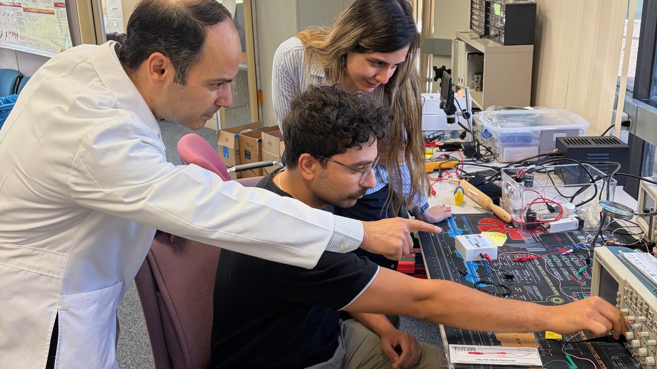 Dr. Hamid Djalilian and student lean over workstation to assist a colleague