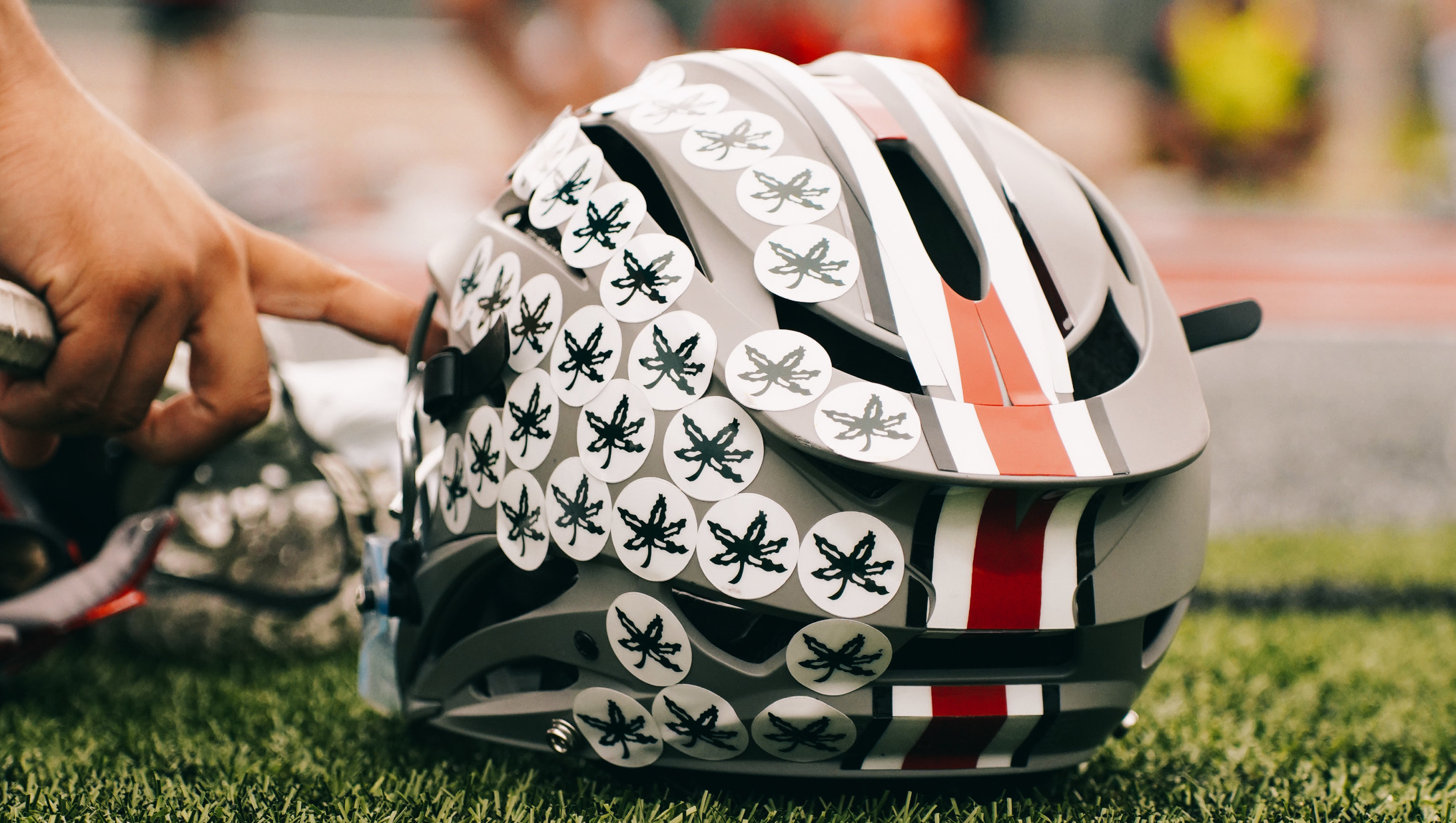 Buckeye lacrosse helmet sitting on green turf
