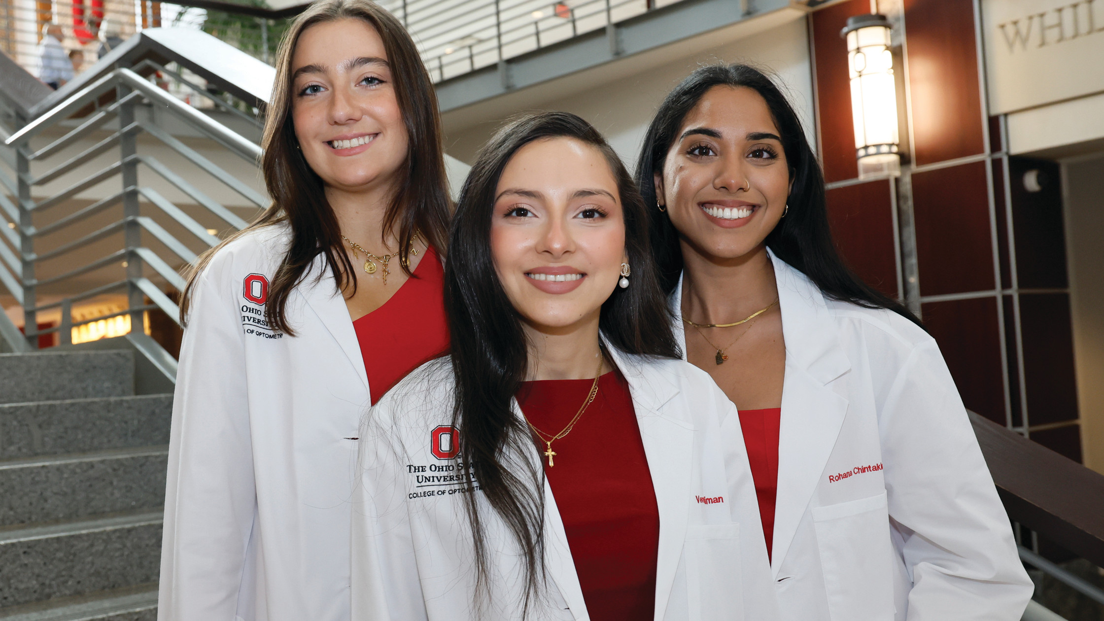 Three female students posing in white coats
