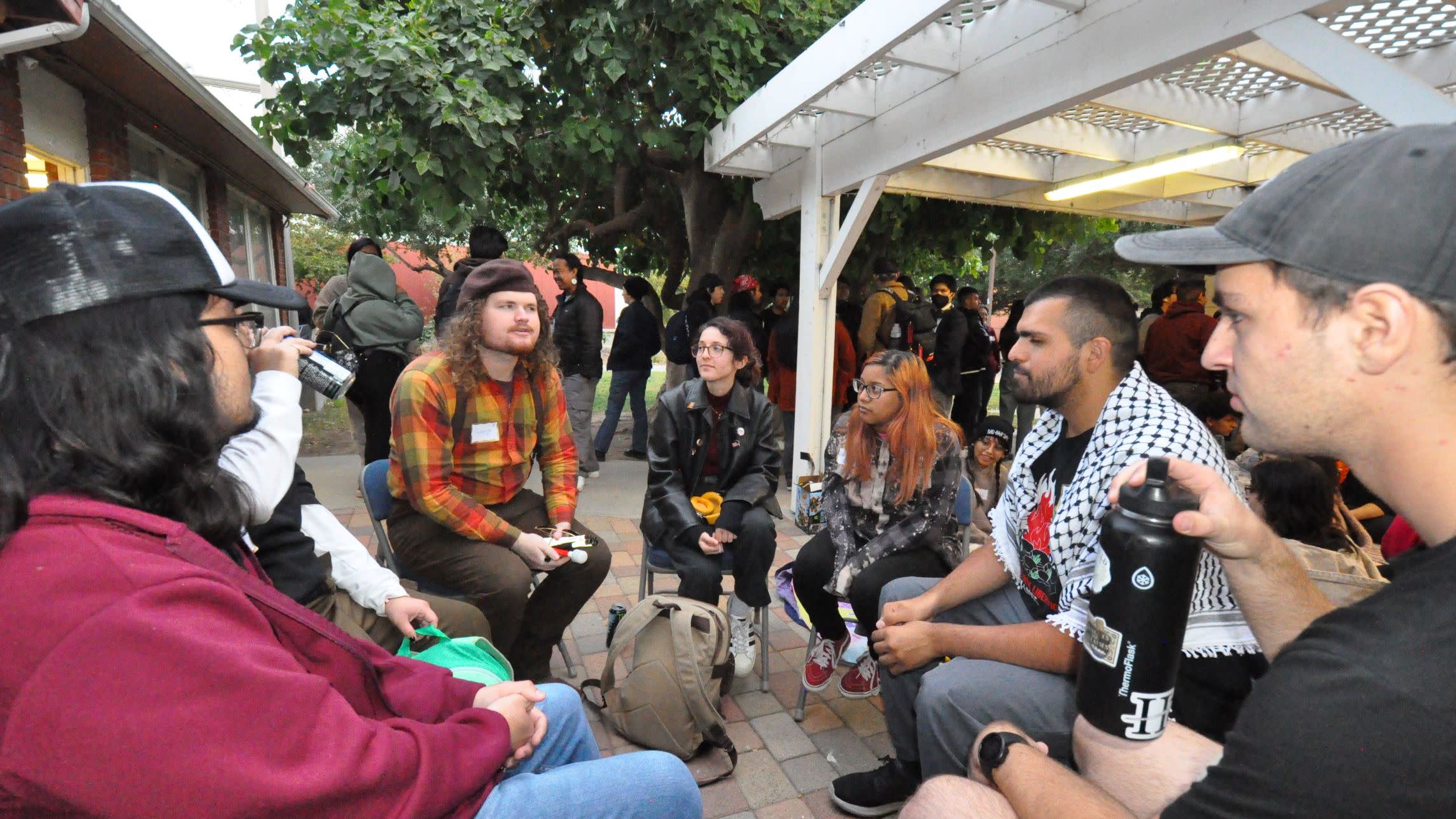 Students gathering, sharing a space together and conversation in outdoor setting.