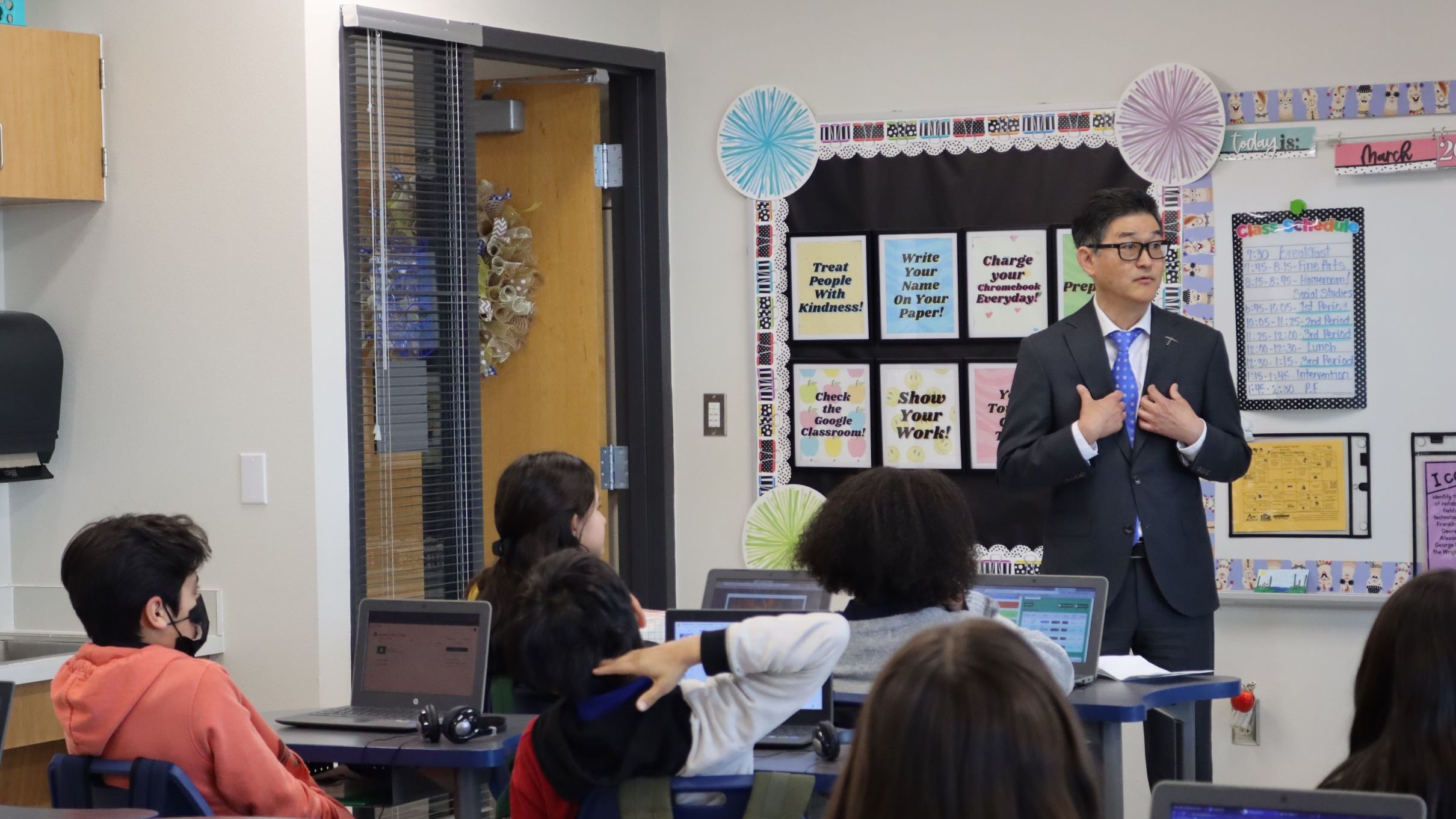 Dean Tanabe stands in front of a small classroom of middle school students.