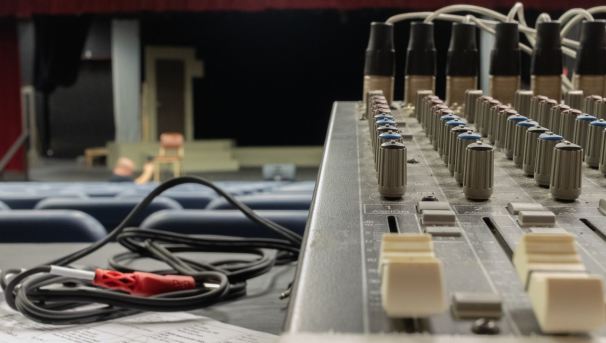 The side view of a soundboard and wires. In the blurred background is an empty stage