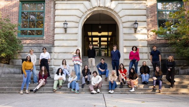 Group of individuals sitting and standing on steps outside of a building
