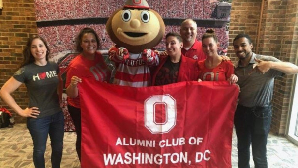 Brutus and six alumni hold an 'Alumni Club of Washington, DC' flag