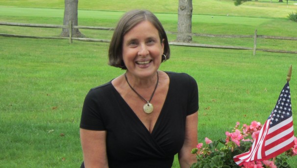 Individual smiling while standing outside wearing sunglasses