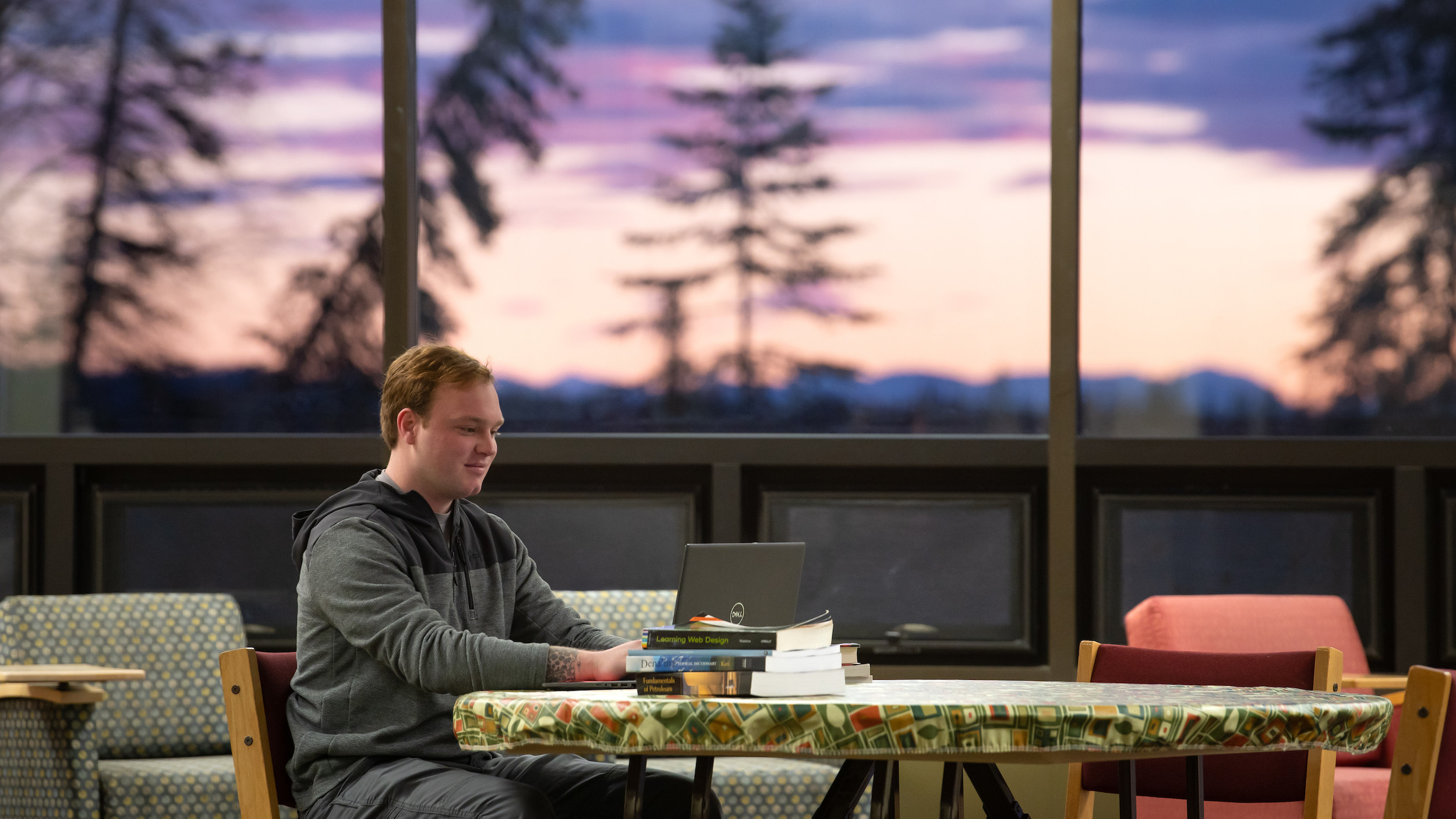 KPC student studying with beautiful pink and purple sunset in the background