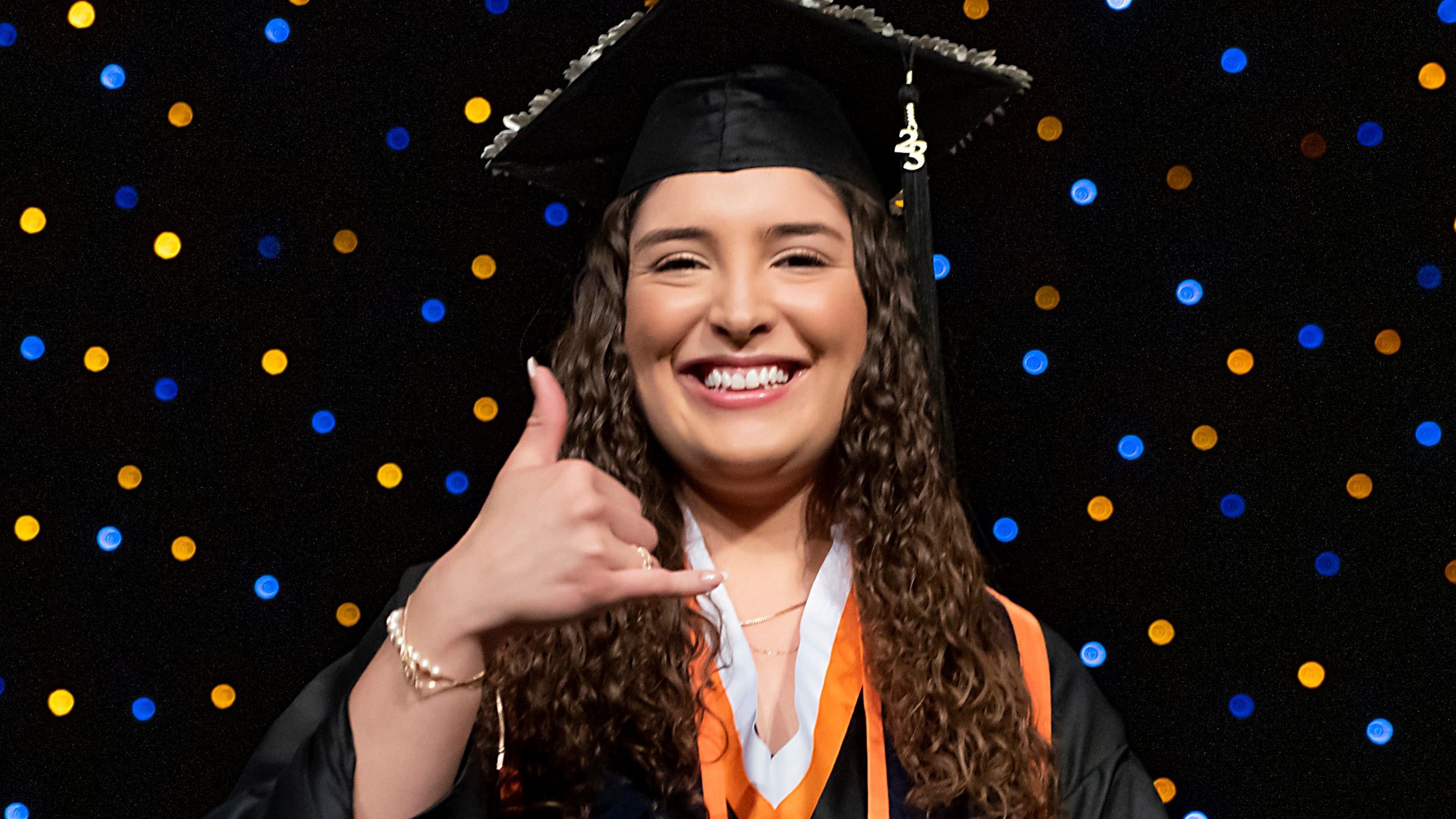 Smiling woman posing with picks up in graduation regalia.