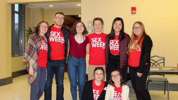 Students smiling towards the camera. Most are wearing red Sex Week 2020 shirts