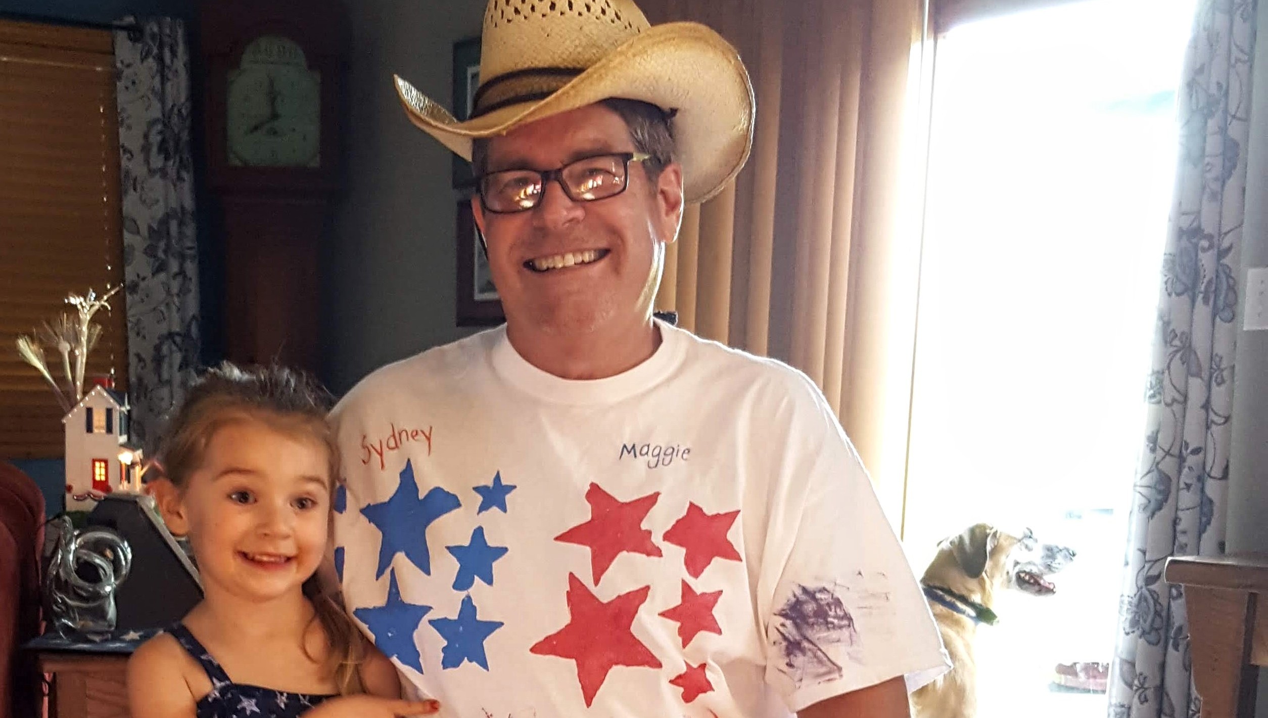 Individual wearing a cowboy hat while a child is sitting next to them