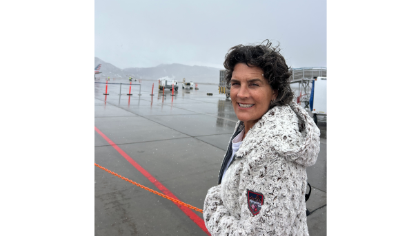 Woman in winter coat stands on airport runway with snow in her hair