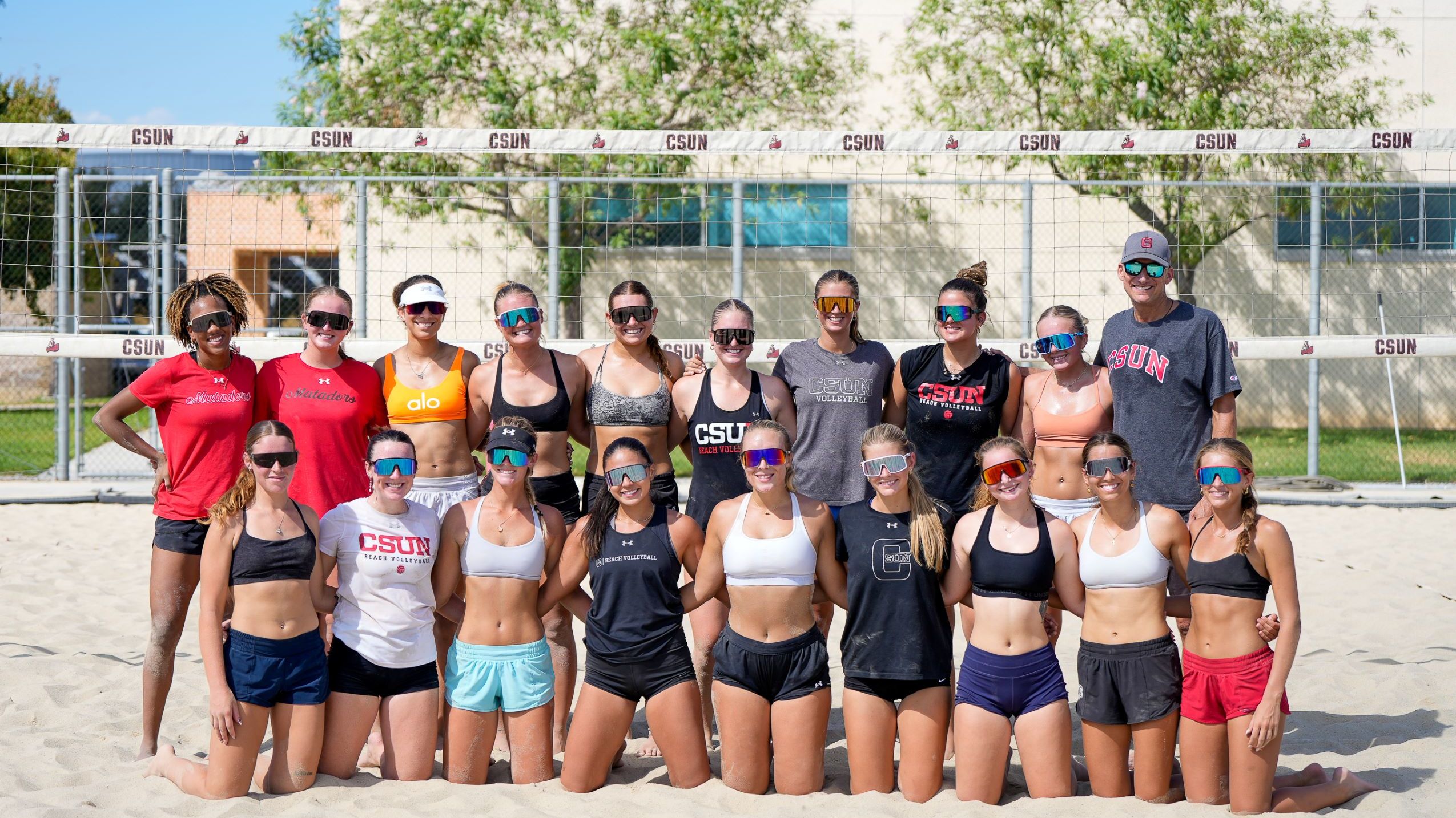 Two beach volleyball players holding hands exchanging words during match.