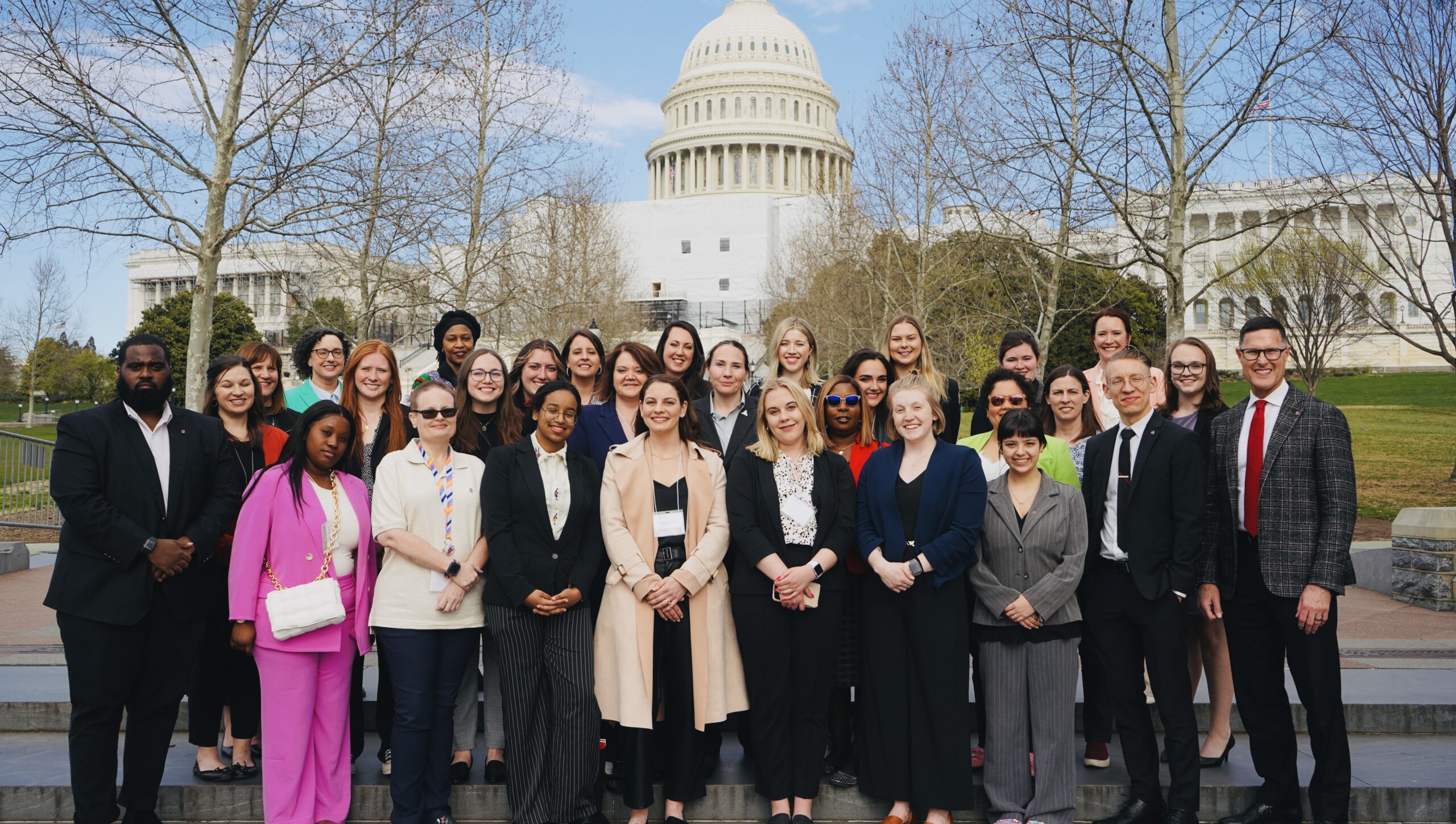 Group of individuals standing outside smiling for a photo