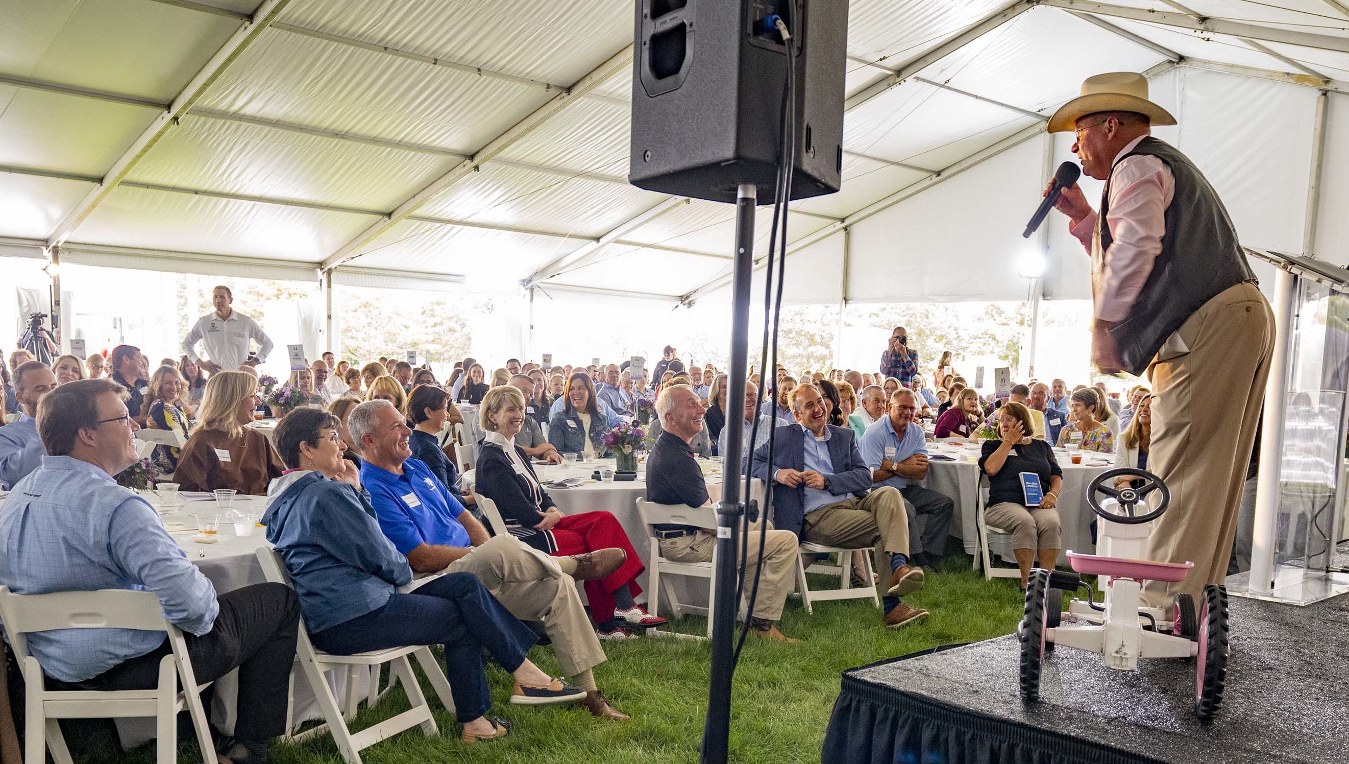 Live auctioneer speaking to a crowd while standing on a stage