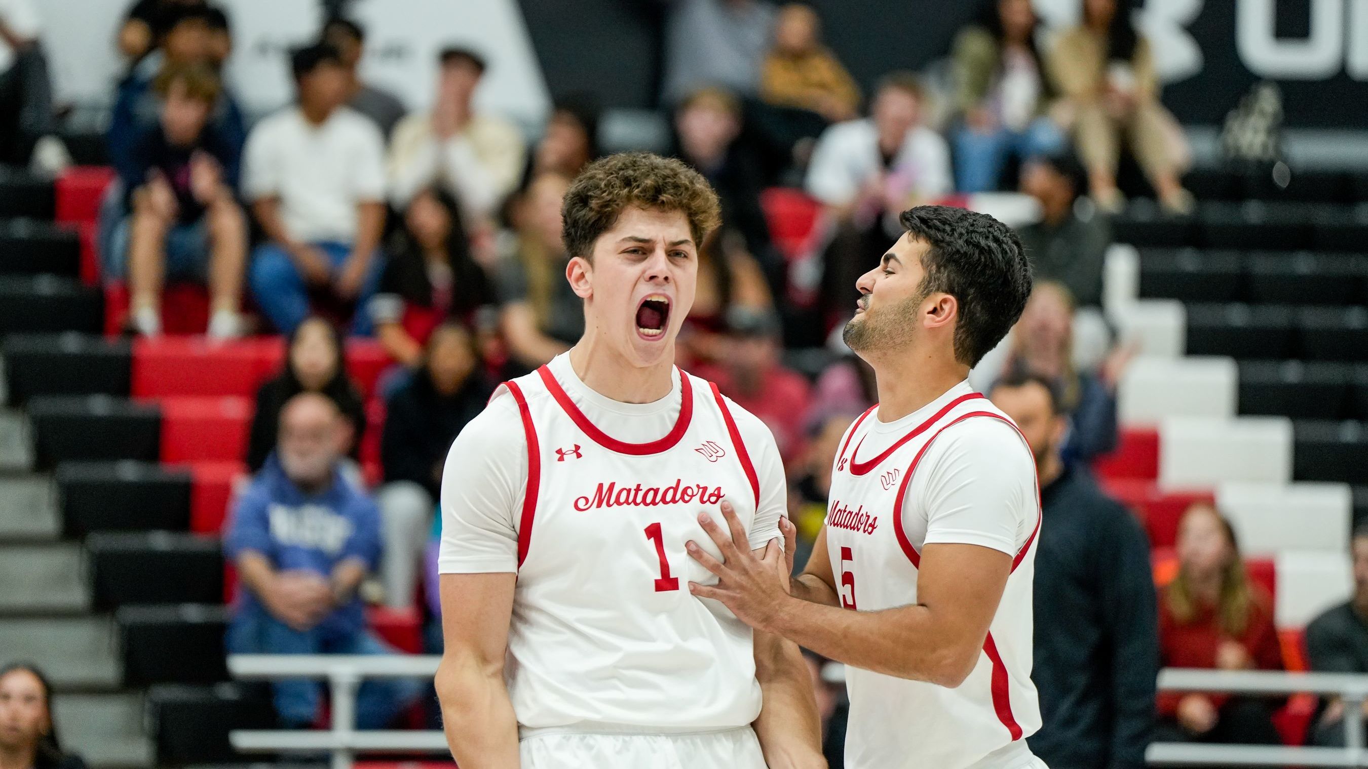 Two Matadors basketball players in white jerseys share an intense moment on the court.