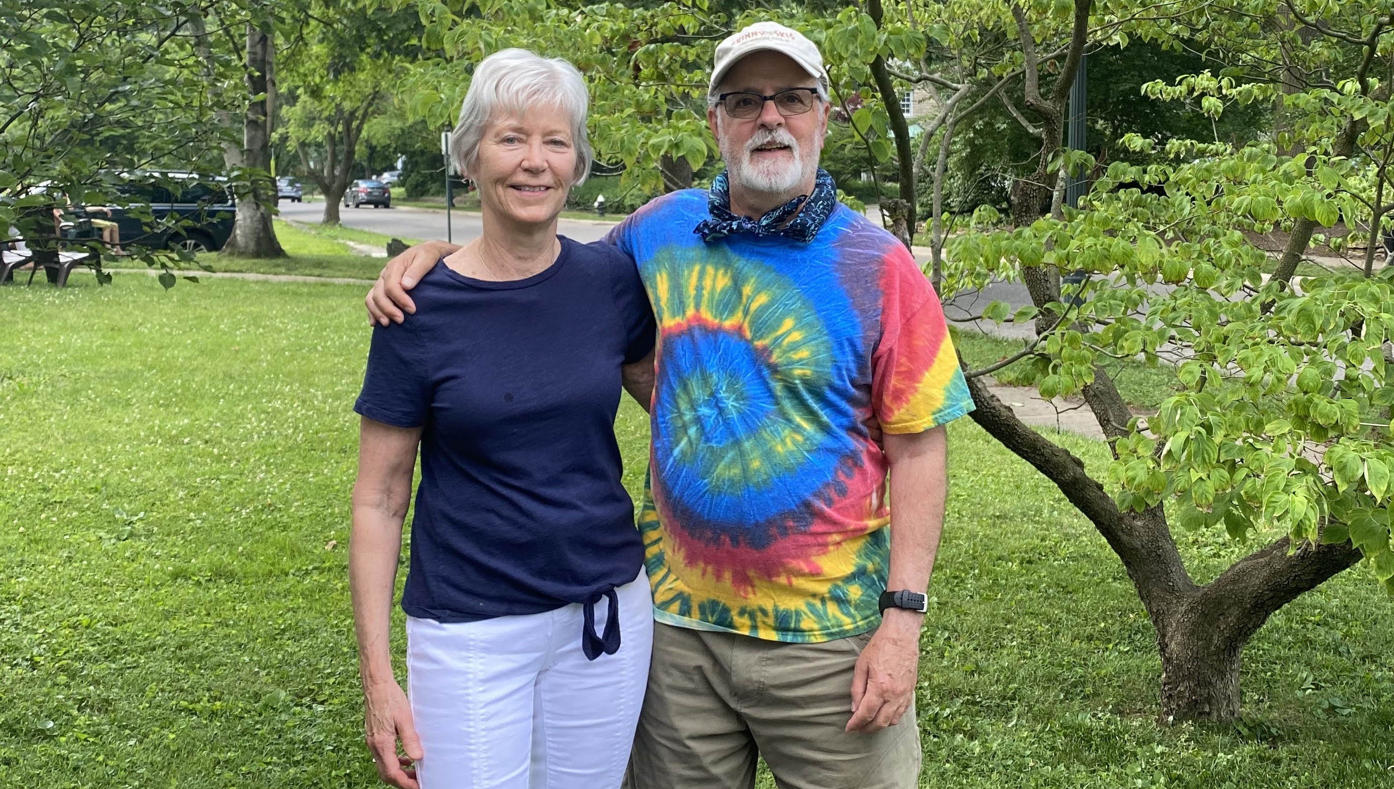 Two individuals stand outside with their arms wrapped around one another