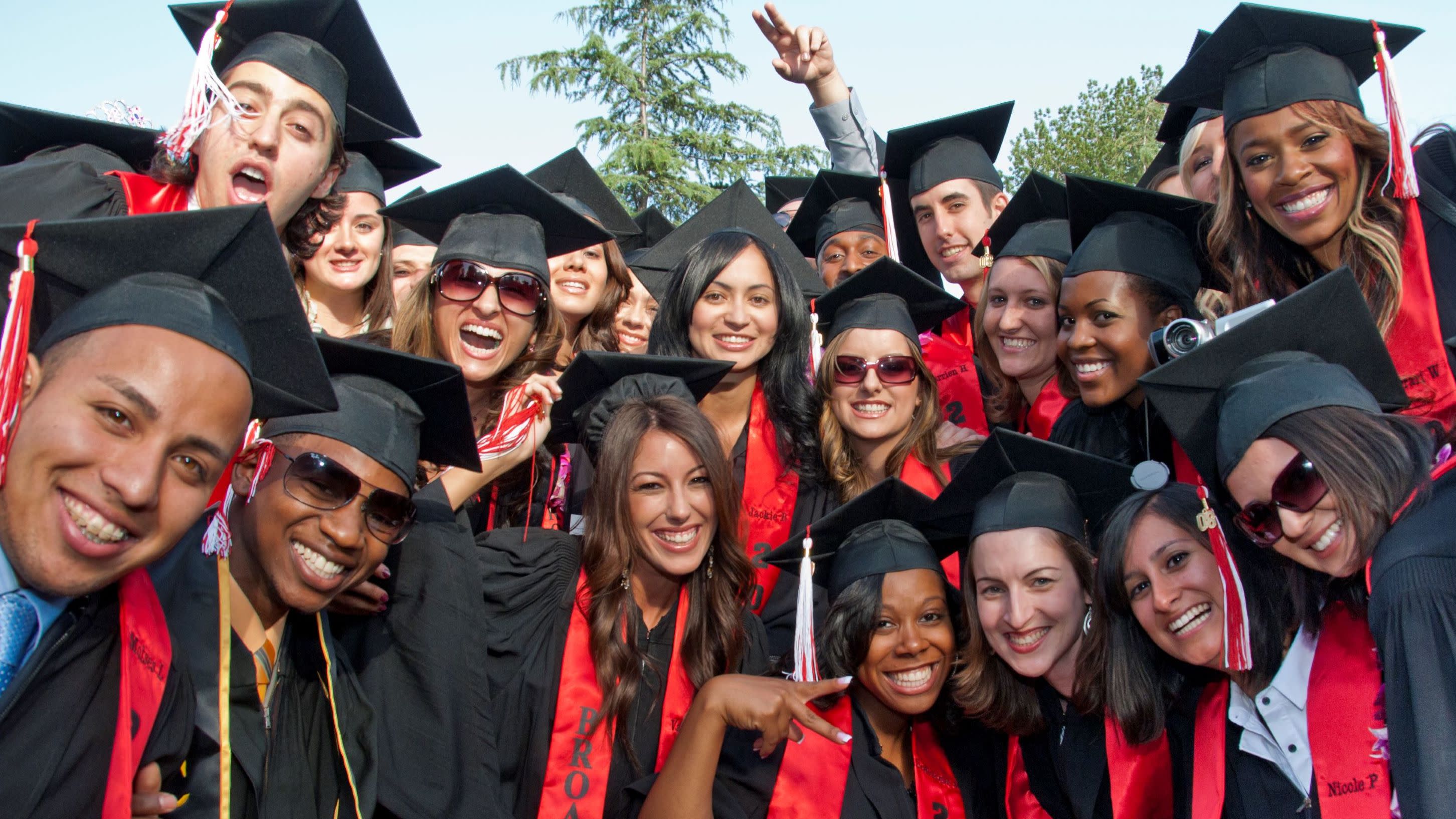 Group of students smiling in graduation regalia.