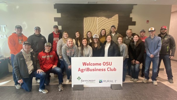 Group of students smiling behind a sign that welcomes the Ohio State AgriBusiness Club