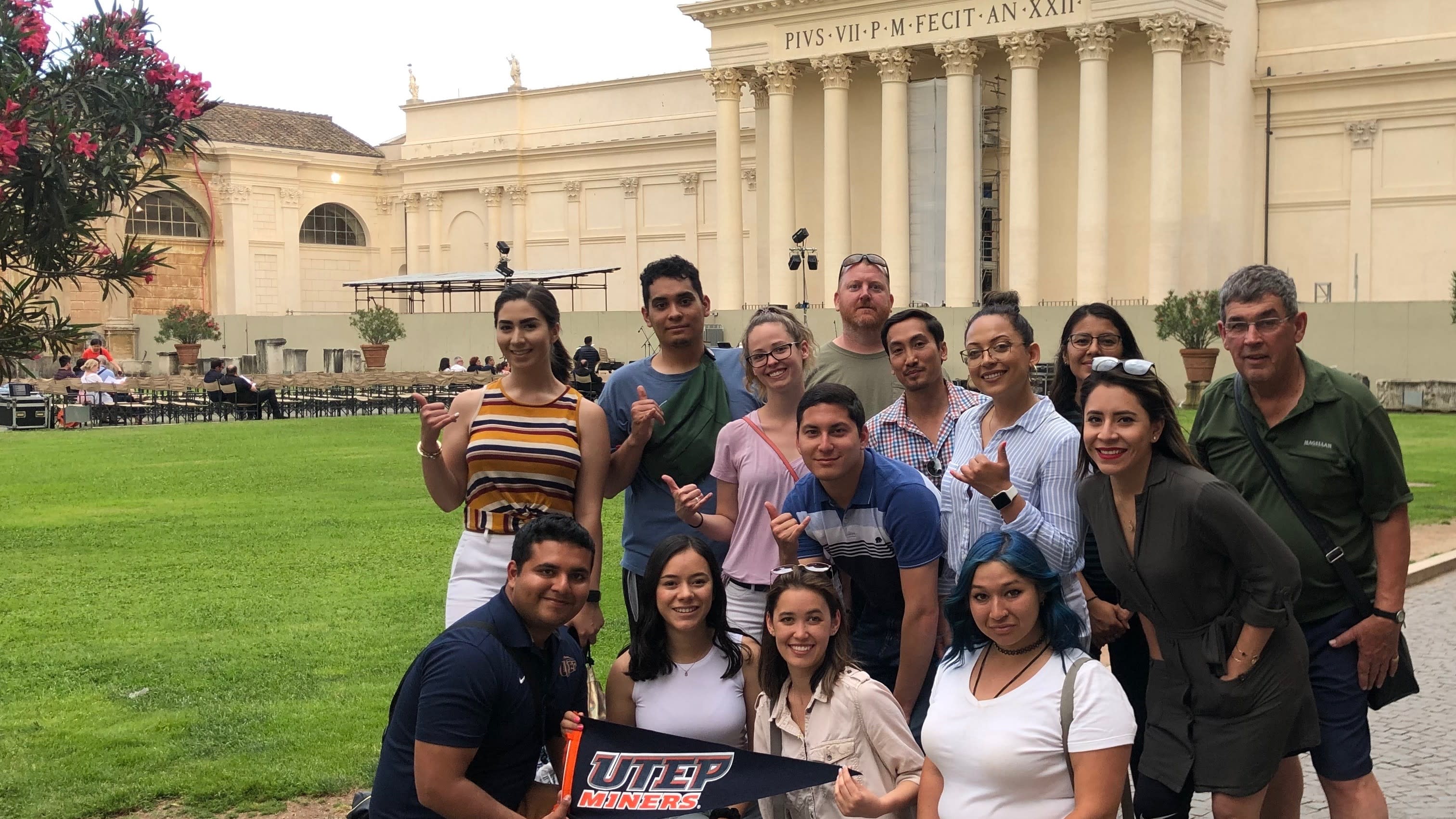 Group photo of UTEP Students holding UTEP Miner pennant in front of the Vatican Museum