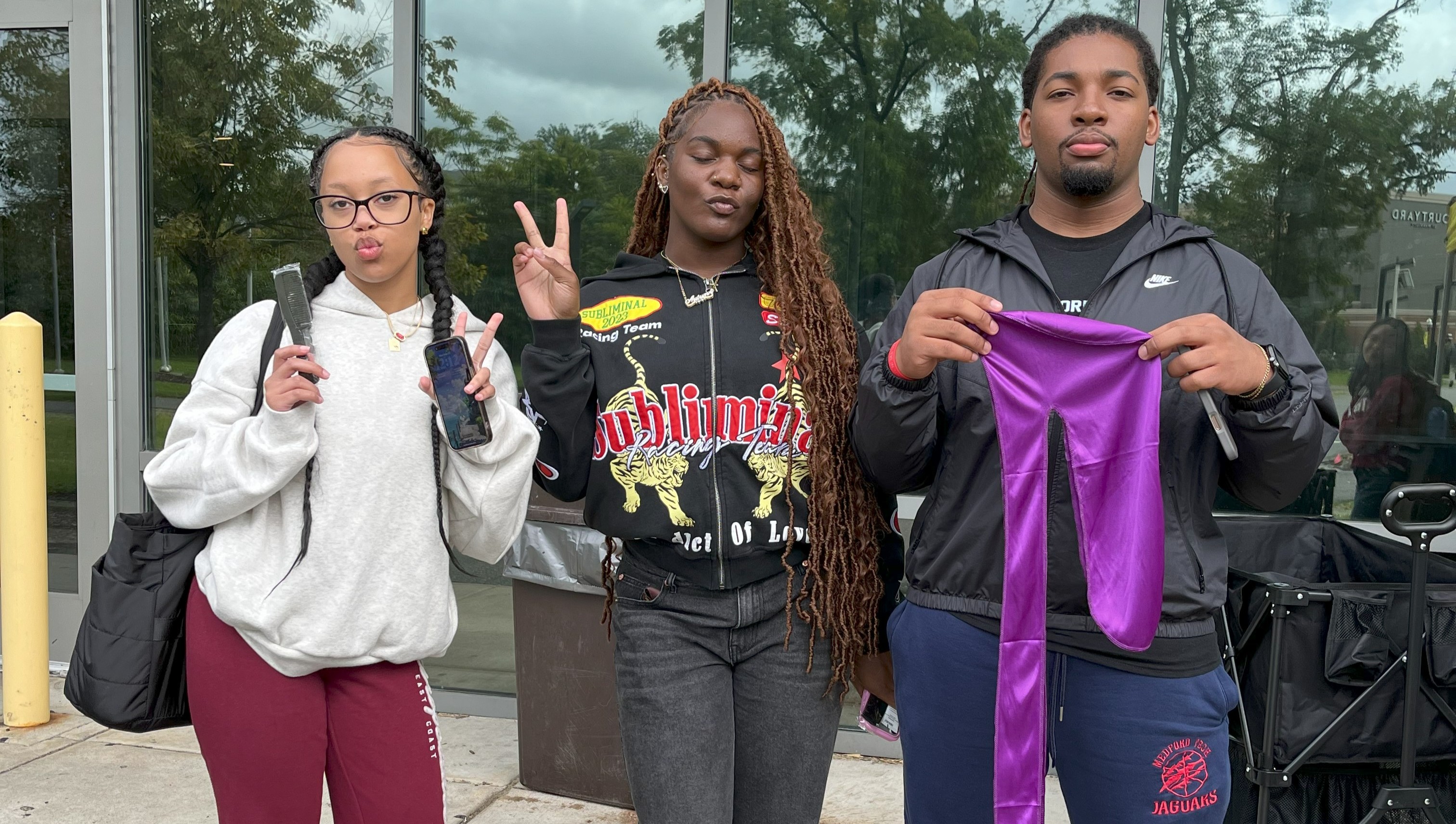 Three students holding durags and brushes received at a Belonging and Care pop up event.