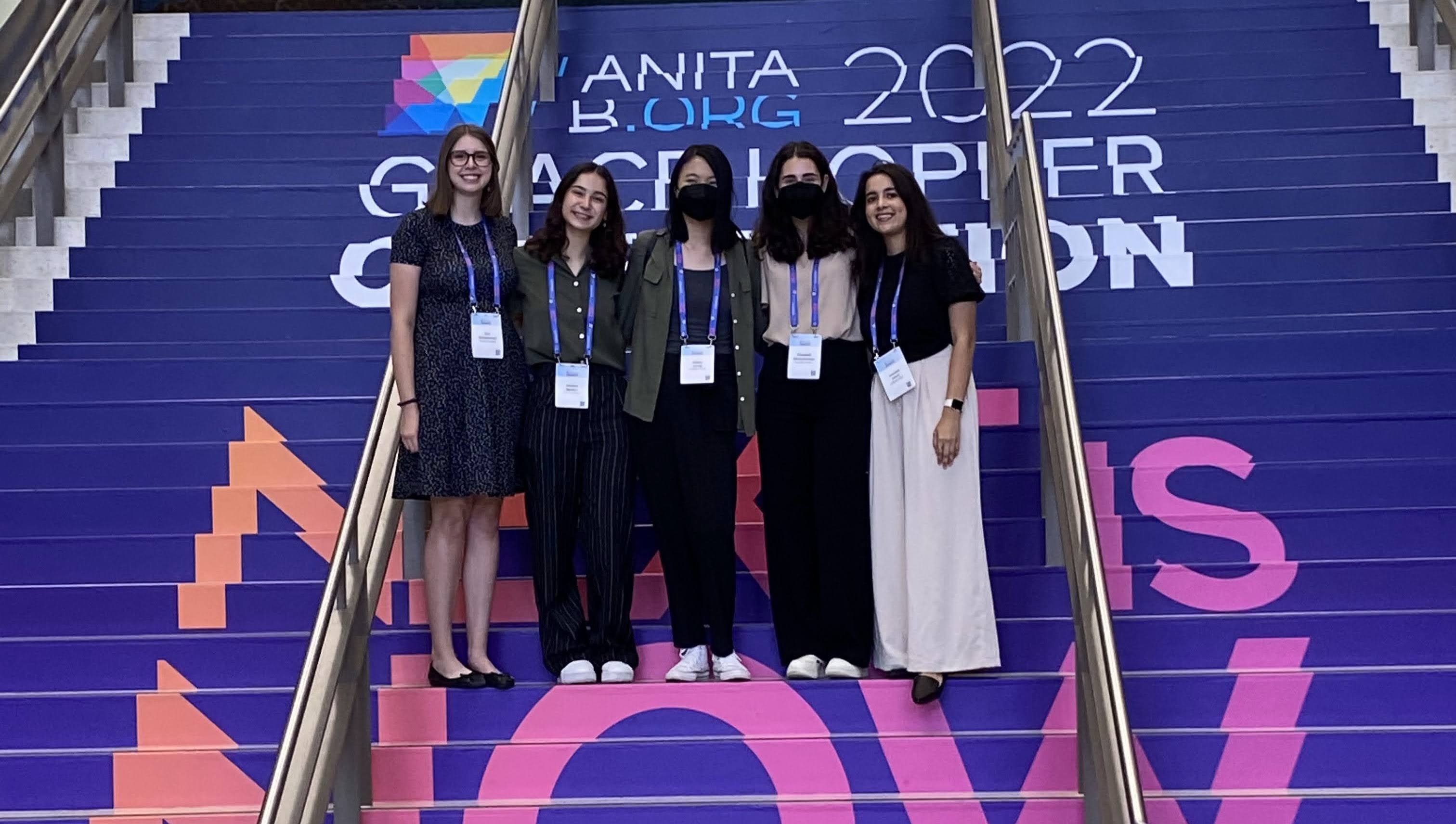 Five individuals standing on steps while smiling at the Grace Hopper Celebration in 2022