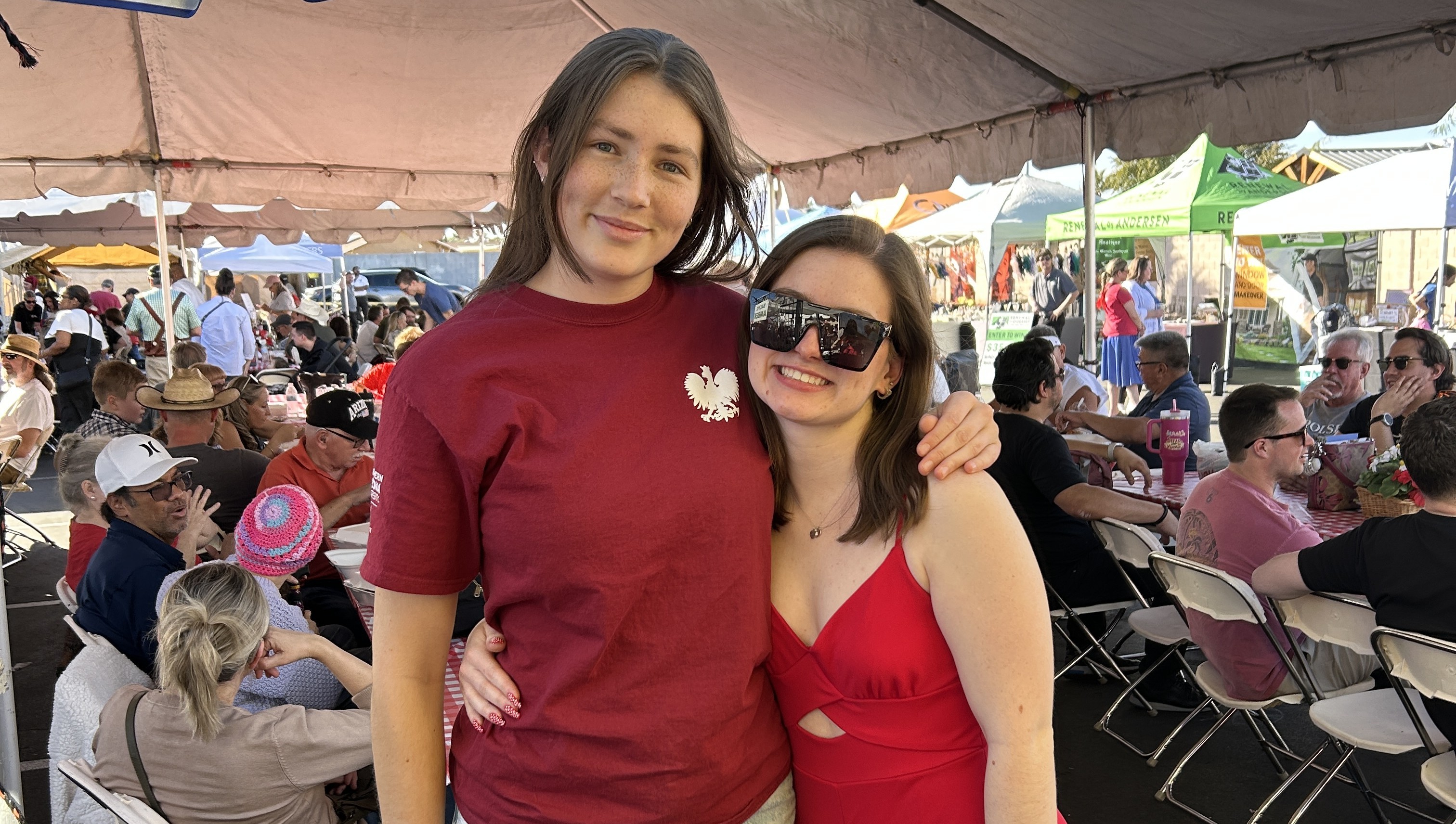 Alex and Secretary Julia stand side by side under a white tent at an event