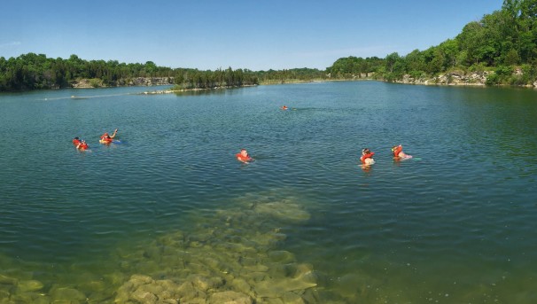 Six campers swimming with bright orange lifejackets