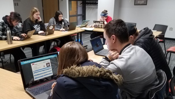 Students in a meeting room using their computers to work on a project