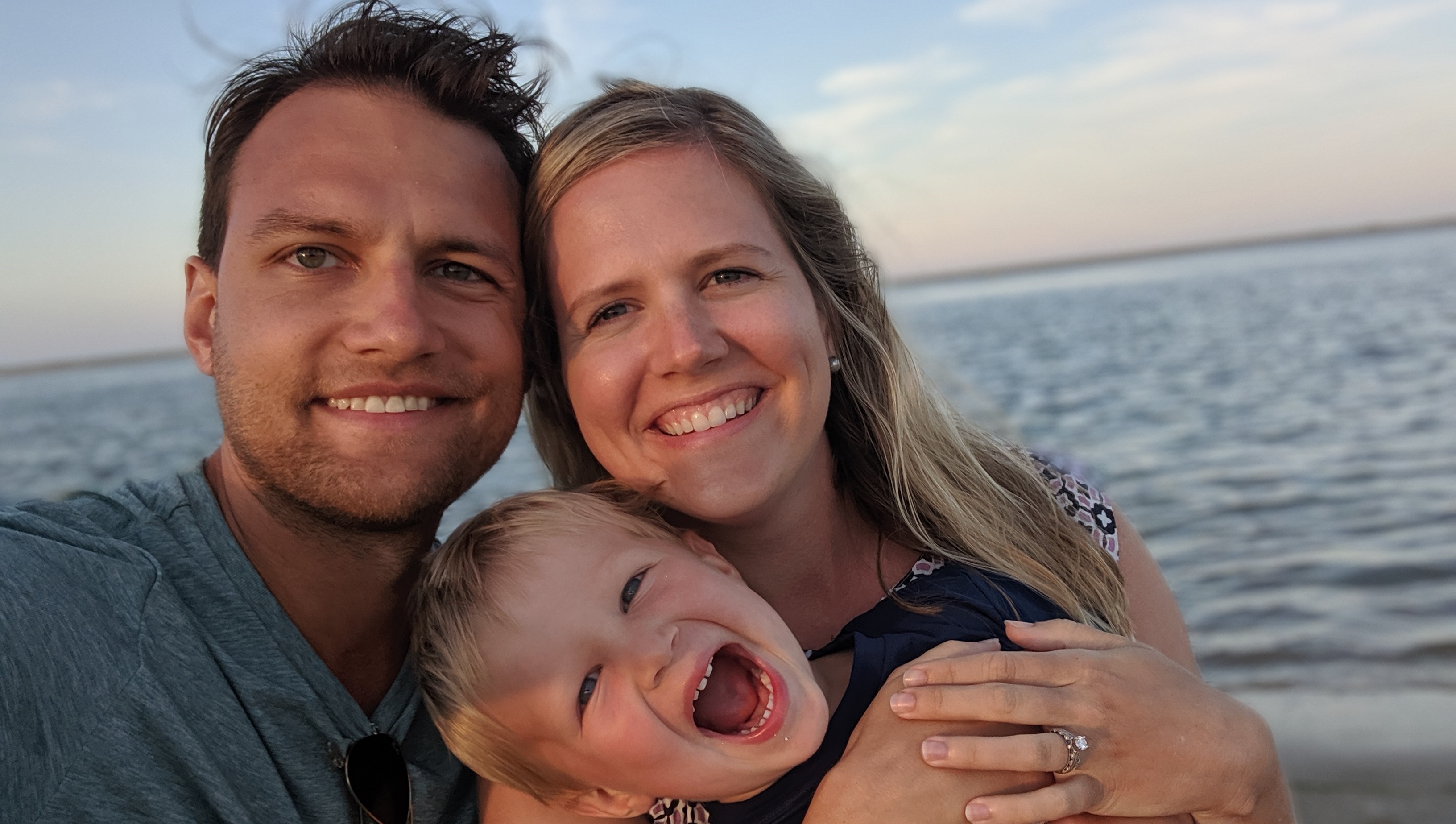 Rob, Rebecca, Rex pose together for a selfie before a calm ocean