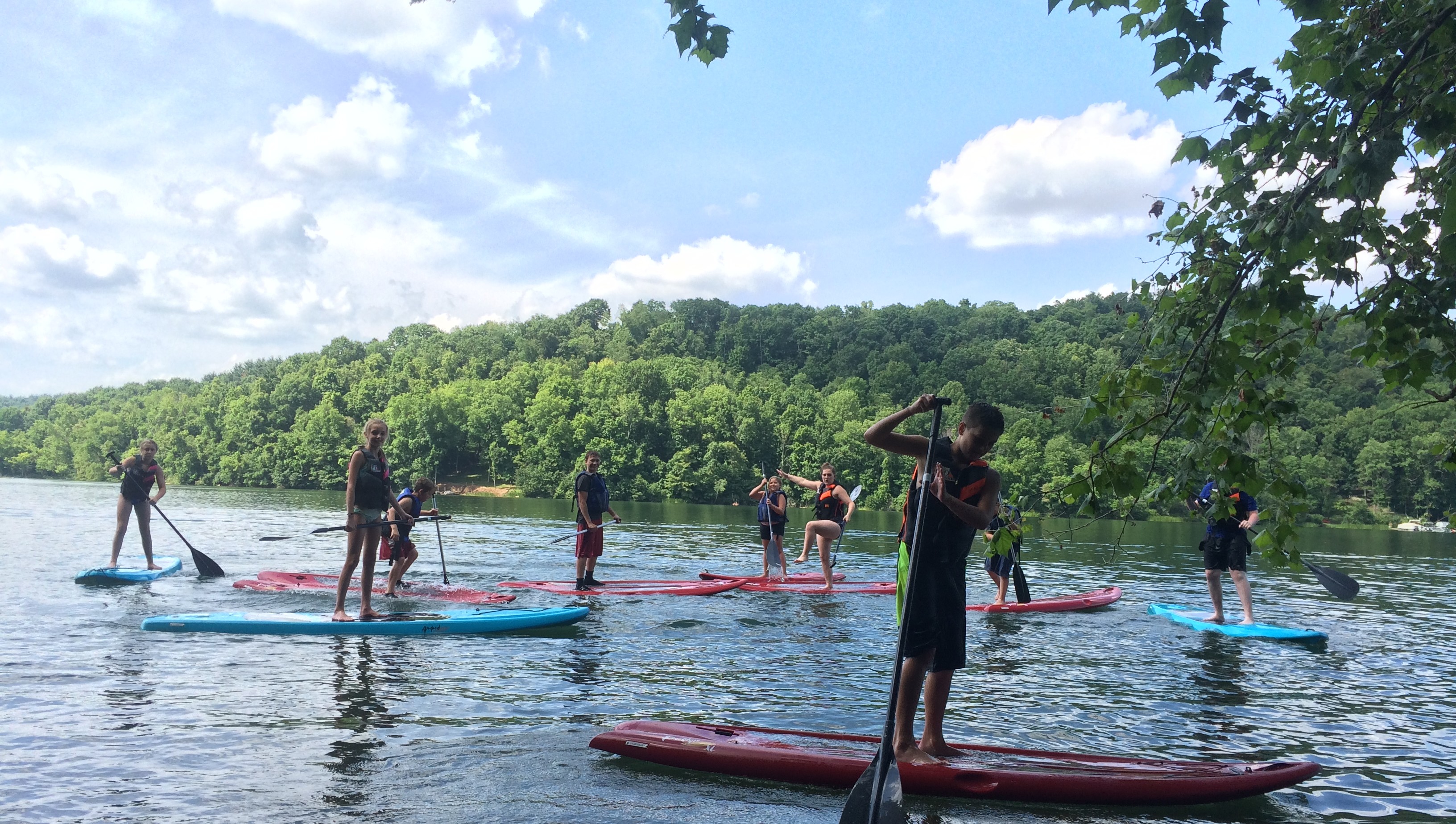 Campers participate in stand up paddle boarding at a lake