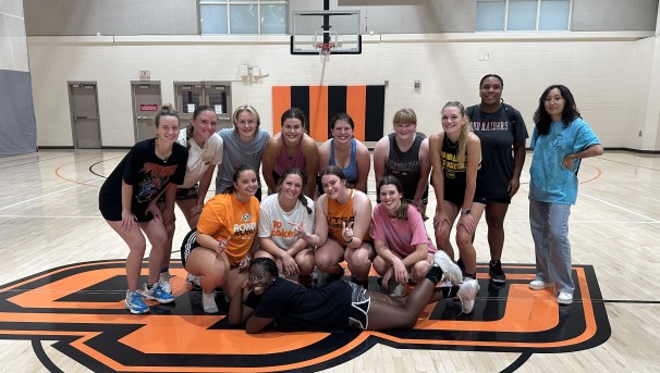 Group of 14 athletes pose on basketball court after practice
