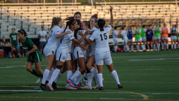 Members of the women's soccer team on the field celebrating.