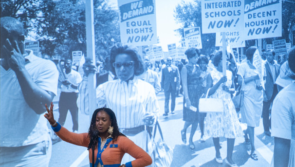 Woman standing in front of the image of a Civil Rights Movement March