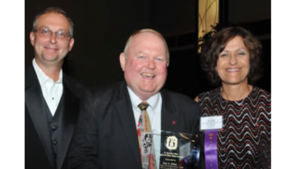 Three individuals smiling for the camera at an awards ceremony