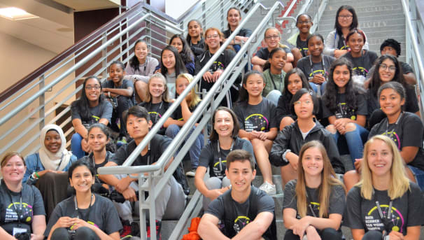 Camp participants and staff sit for a group photo on the stairs