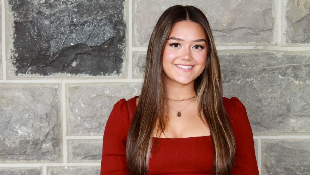 Kylie stands smiling in front of a Hokie Stone wall